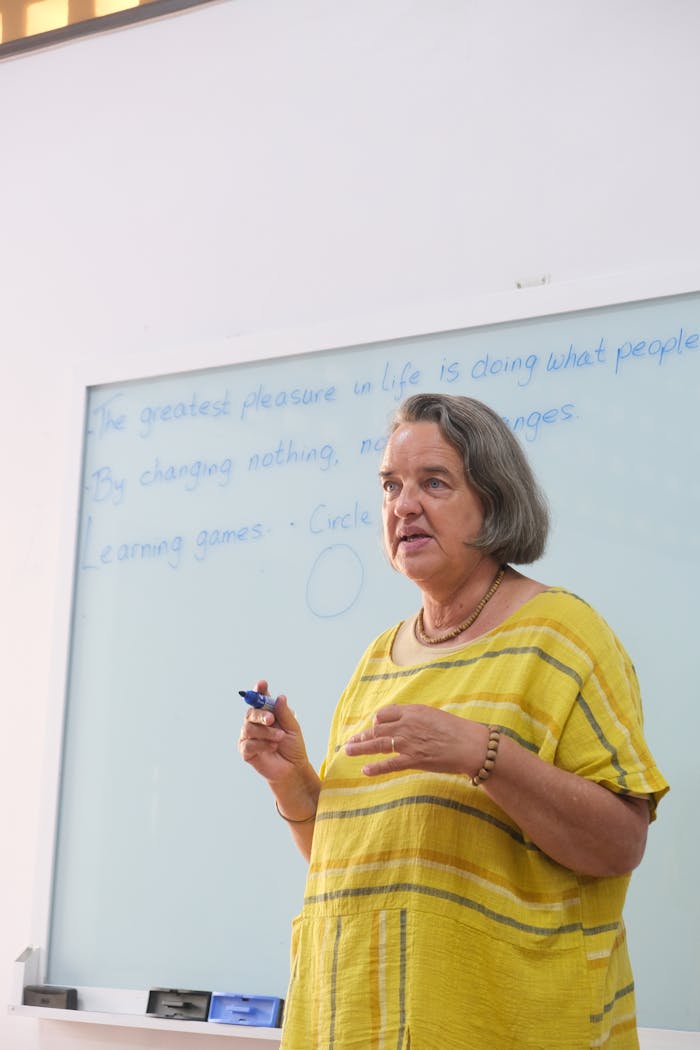 who-we-are A teacher delivering an interactive lecture in a classroom setting, engaging students with a whiteboard.